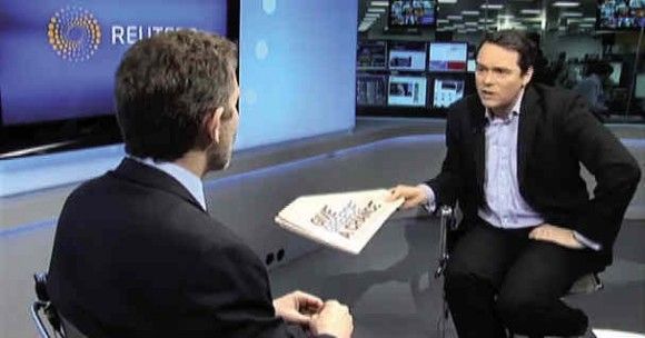 Reuters reporter holds a newspaper with the “Greece is Changing” ad during a recent interview with Culture and Tourism Minister Pavlos Yeroulanos (left).