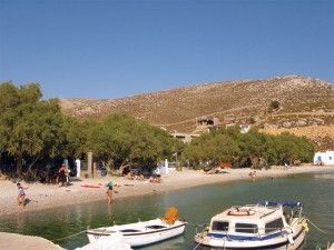 Vlihadia - A long beach shaded by trees and small anchored boats.