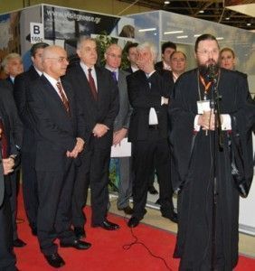 Greek Secretary General of Tourism Anastasios Liaskos (left) looks on as the representative of the Holy Synod of the Church of Greece and Secretary of the Synod office of pilgrimage tours Archimandrite Spyridon Katramados gives a speech at the inauguration ceremony of the GNTO stand at MITT 2013. Photo source: http://www.ecclesia.gr