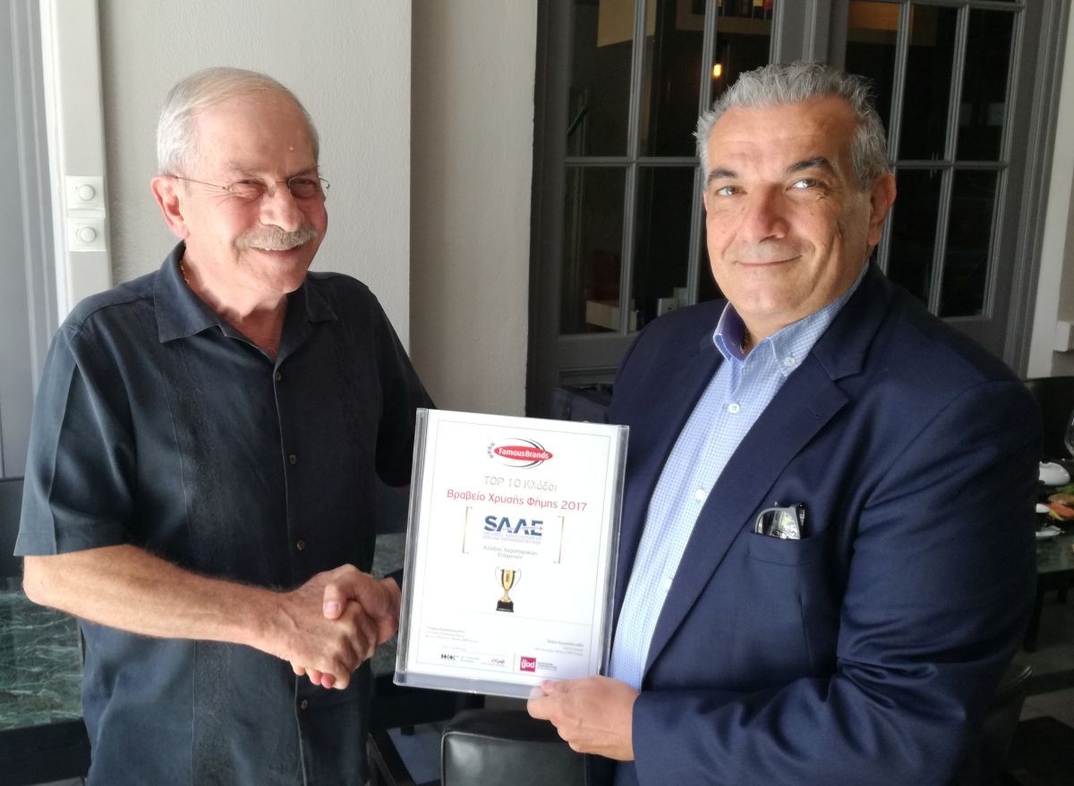 SAAE's outgoing president, Giorgos Antonaros (R), handing the Famous Brand 2018 award, recently won by the association, to new president, Dinos Frantzeskakis.