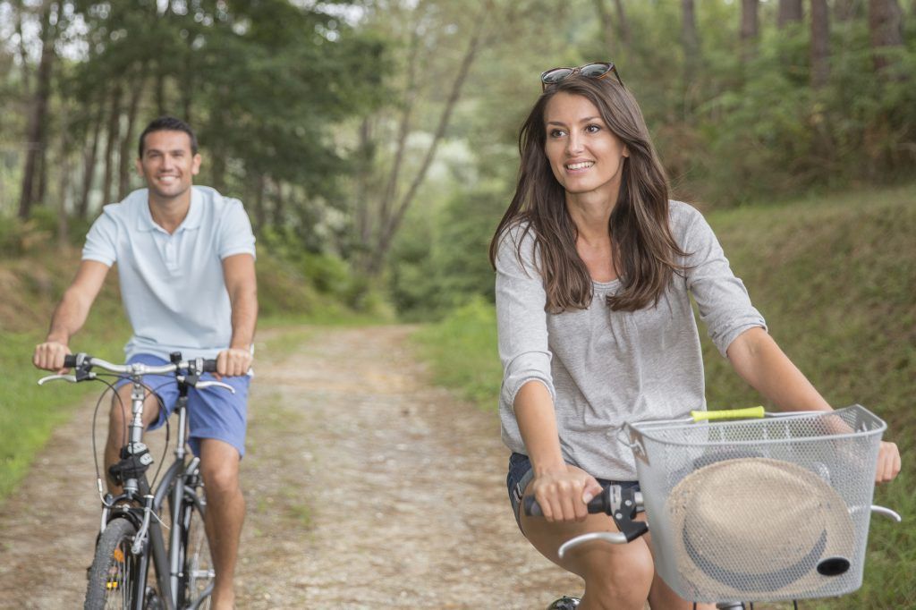 man and woman cycling in forest road