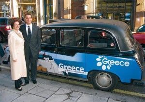 Sofia Vasiliou, GNTO's general director of promotion; and Makis Peppas, GNTO director for the U.K. & Ireland, next to a taxi cab in London parked outside GNTO London offices. The cab displays part of the organization's advertising campaign in an effort to attract British visitors to Greece.